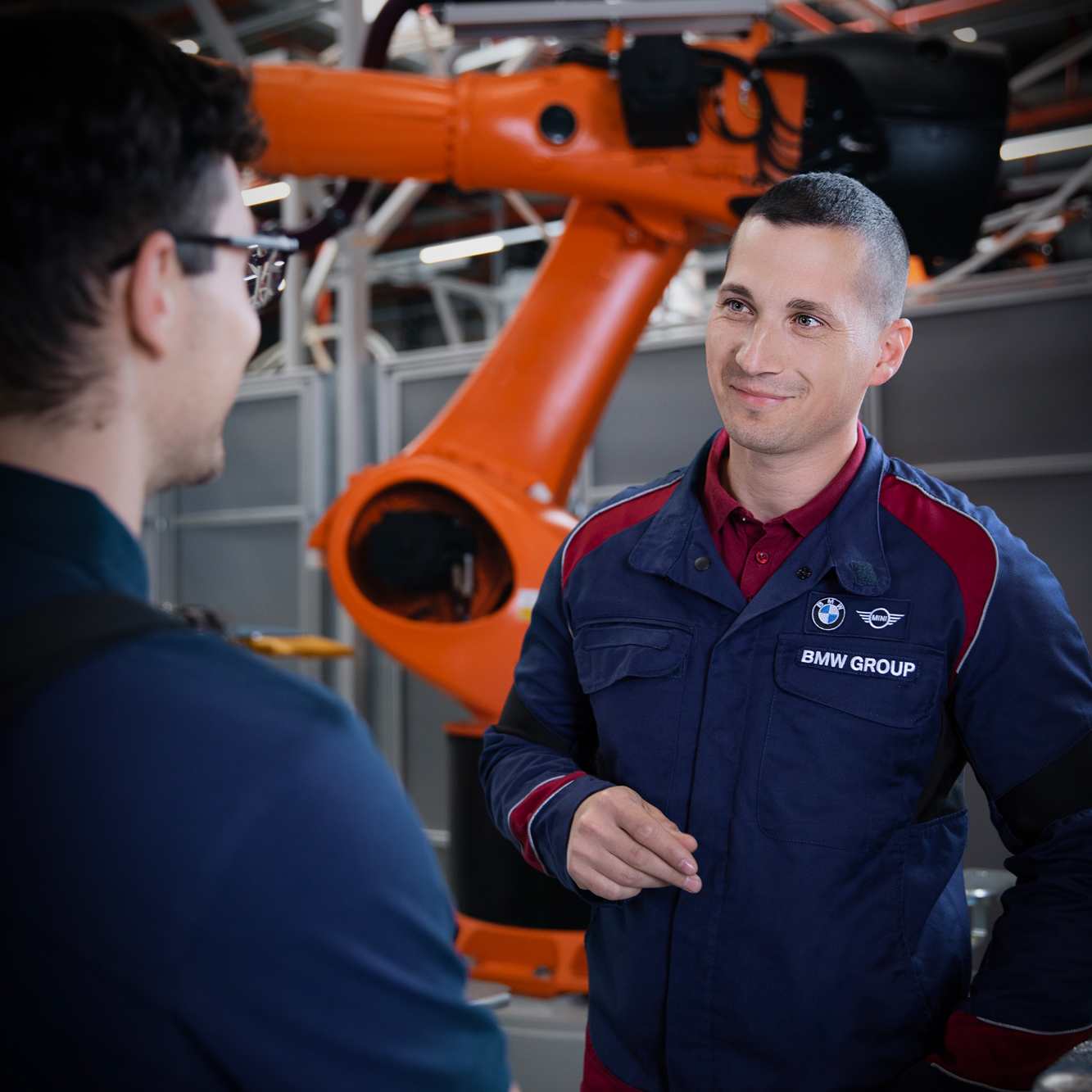 Two maintenance workers are having a conversation in front of a robot