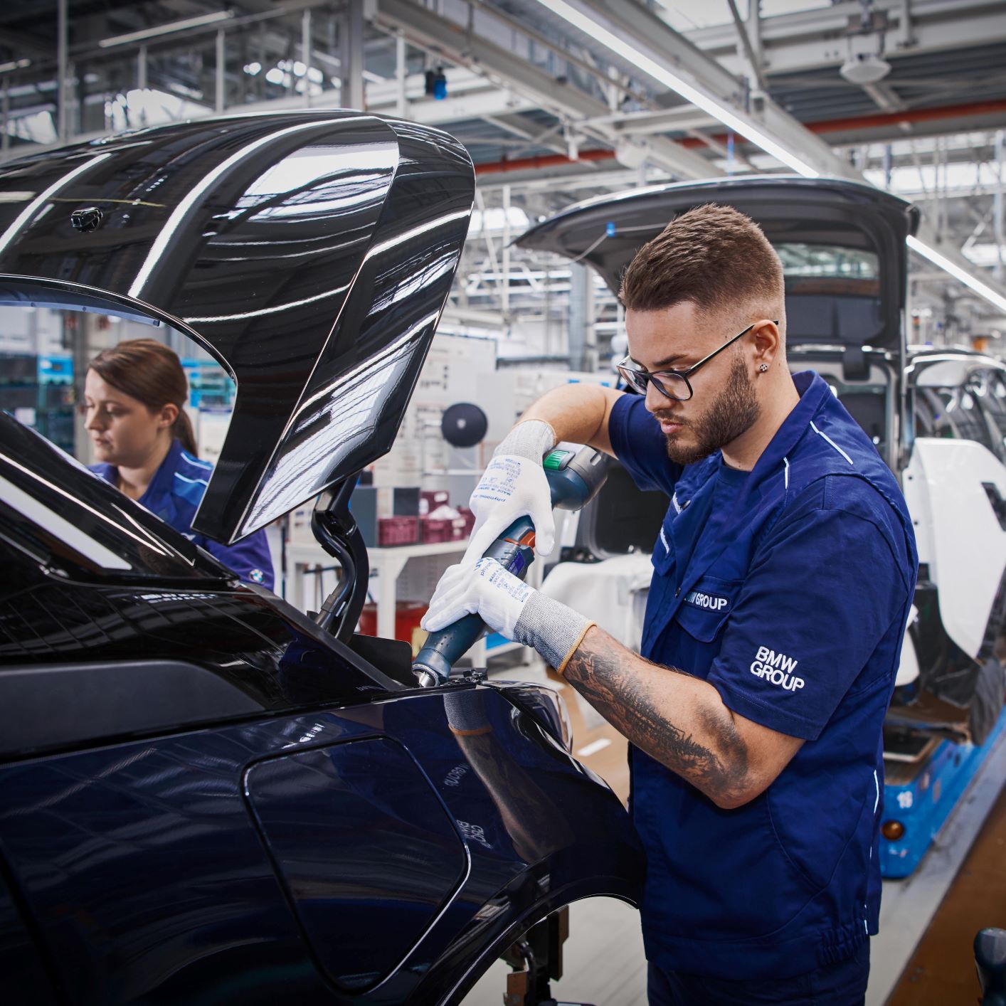 A production worker is assembling parts on a car