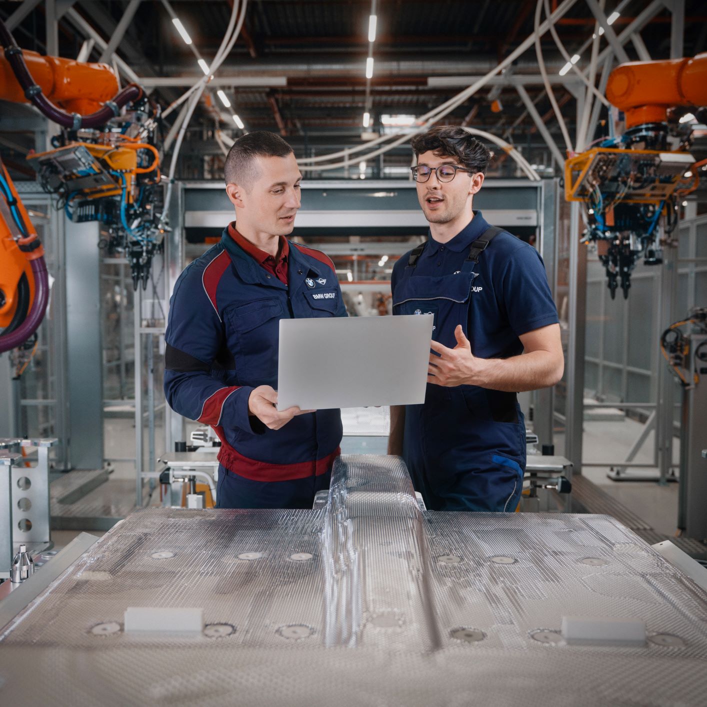 Two maintenance workers have a conversation in a robot hall