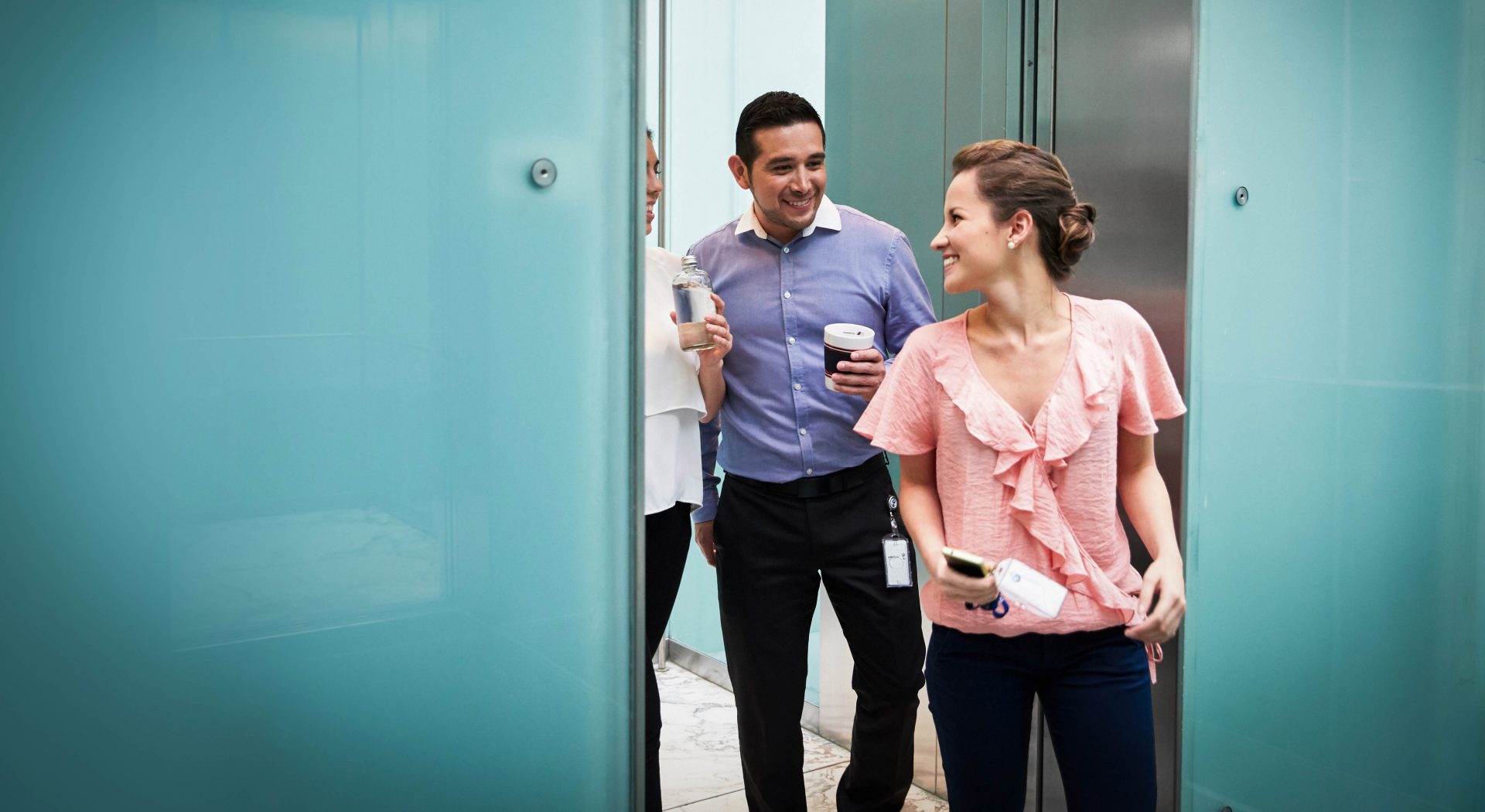 The picture shows three laughing BMW employees talking to each other.