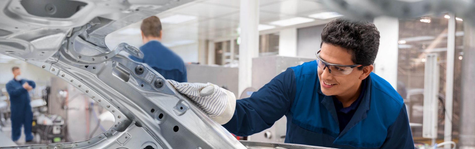 BMW employees during assembly work on the rear of a BMW.