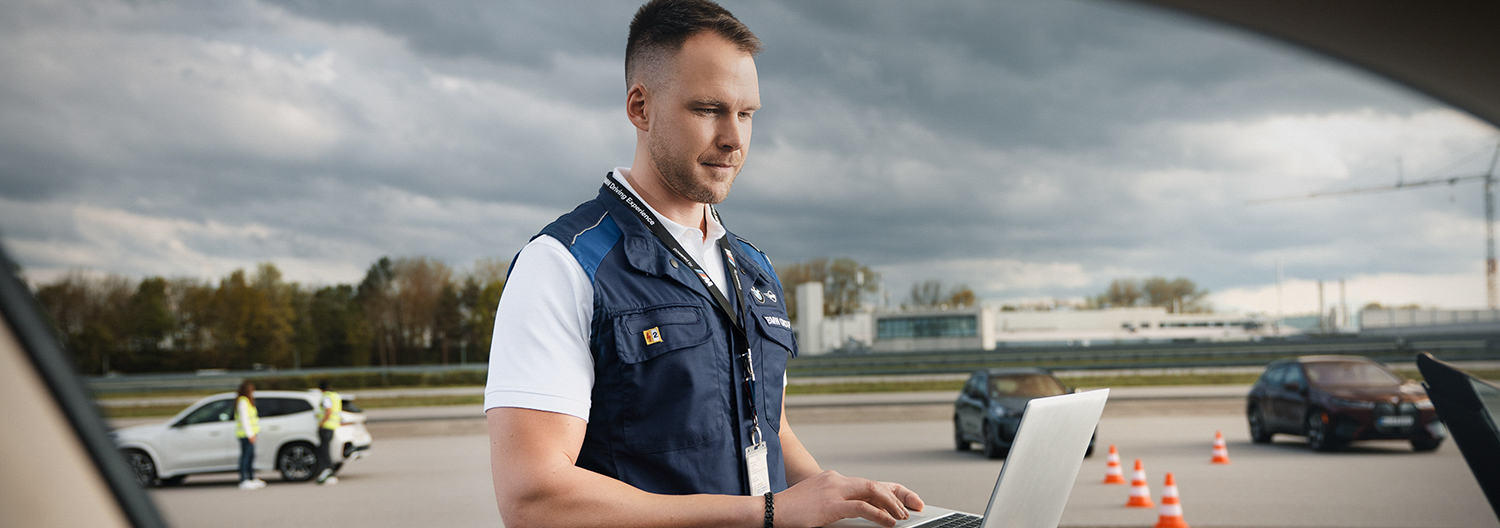 An engineer is working on a laptop on the test track.