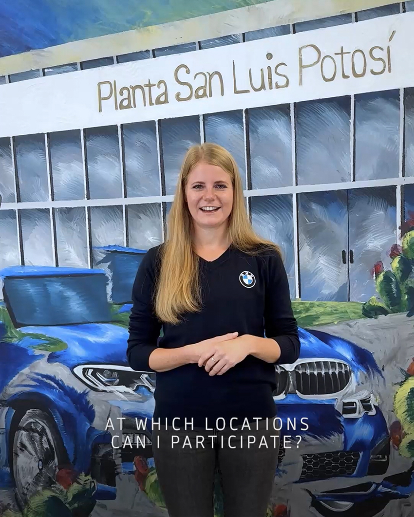 A female trainee infront of a painting of the BMW Group Plant San Luis Potosi answering the question "At which locations can I participate?"
