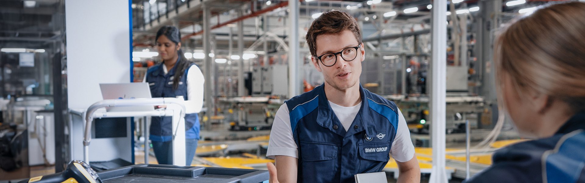A BMW Group working student in production is having a chat with a colleague.