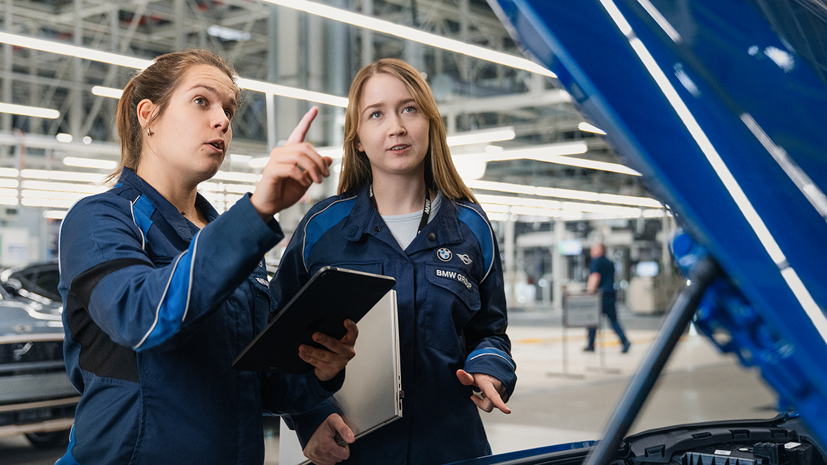 Two female colleagues, one of them a little older than the other, inspecting a car