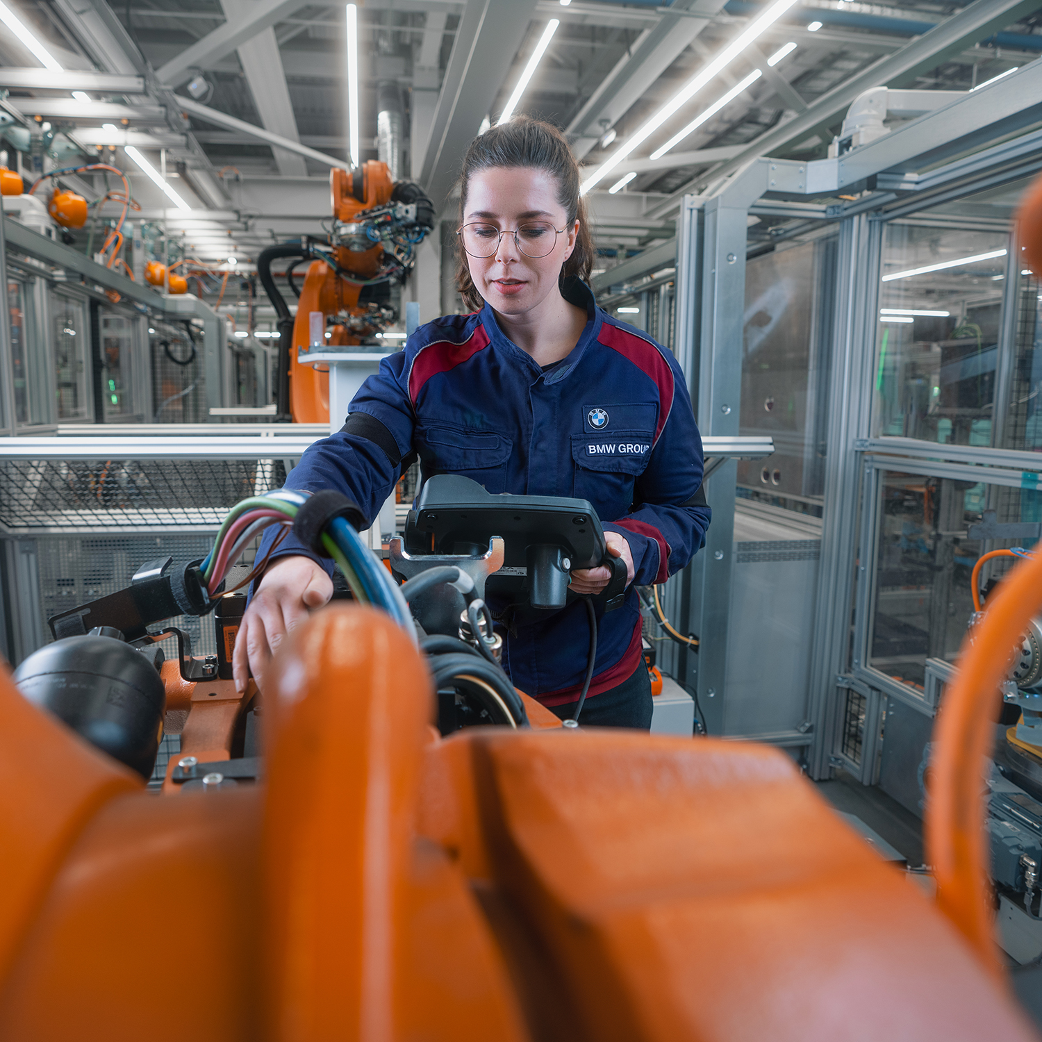 A female maintenance technician is working with a robot.