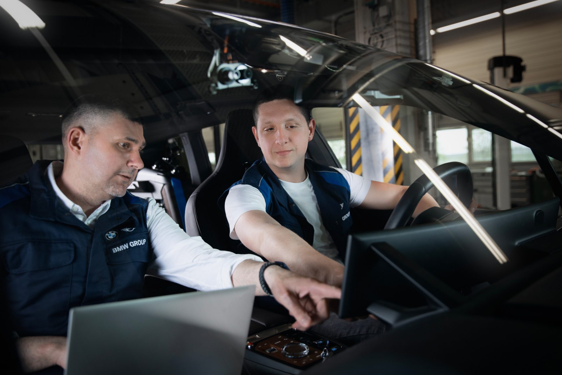 Two BMW Group engineers work in a car.