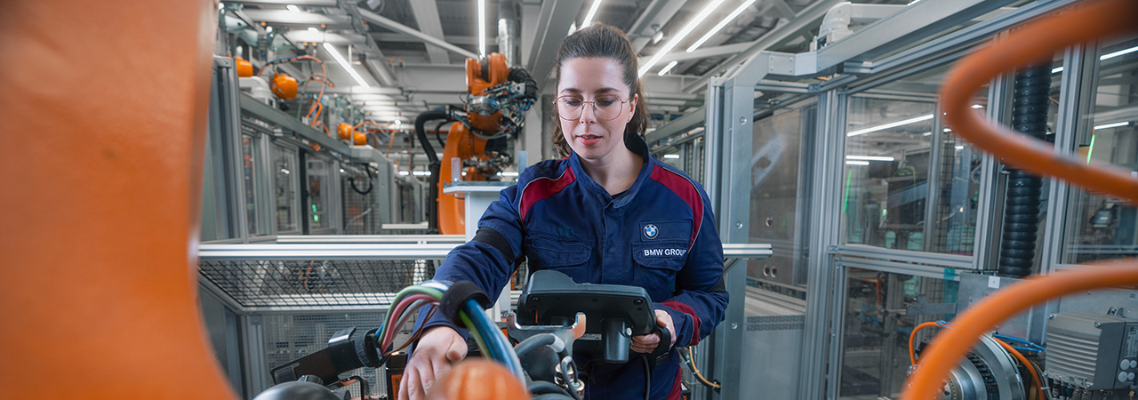 A female maintenance technician is working with a robot.