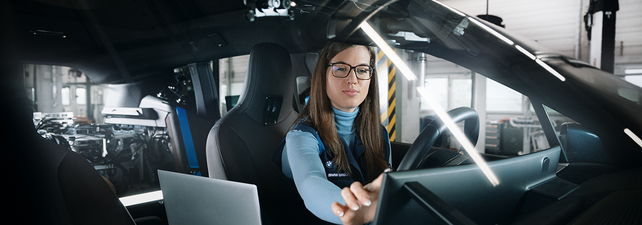 A female IT software developer is working in a car.
