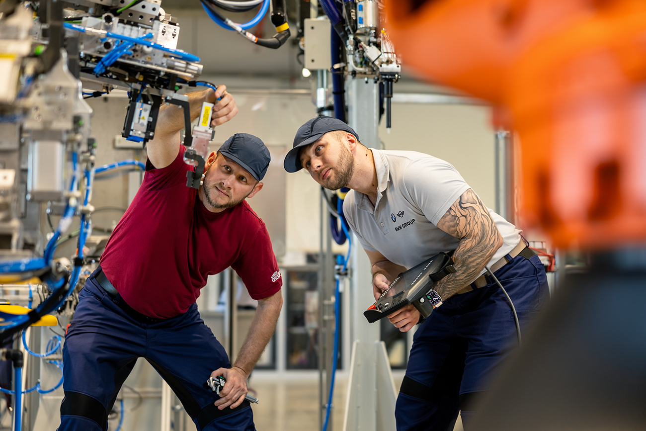 Two BMW Group employees working at a car energy module