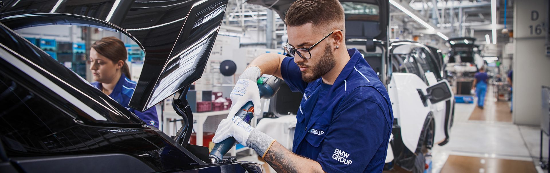 Két BMW-alkalmazott dolgozik egy BMW hátulján.