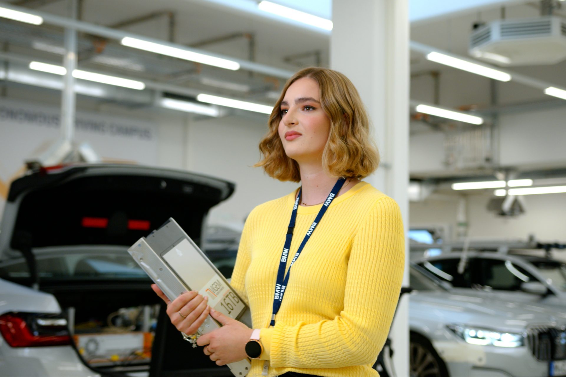 A BMW Group intern walking through a hall with cars.