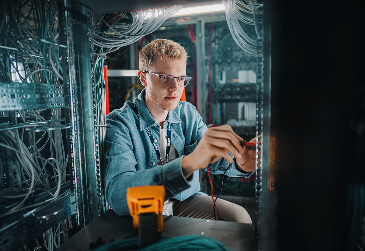 Egy gyakornok a termelés szerverteremében dolgozik.