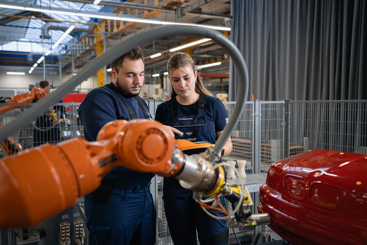 Két gyakornok dolgozik egy ipari roboton