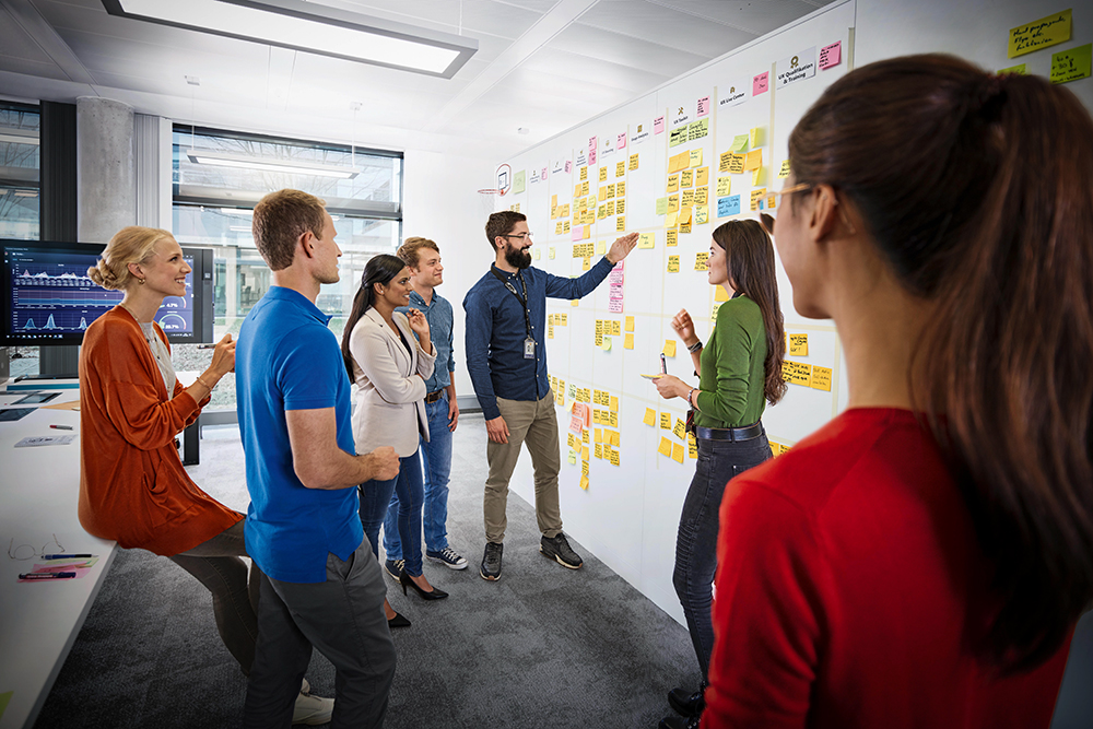 A group of BMW Group employees in a stand-up meeting.