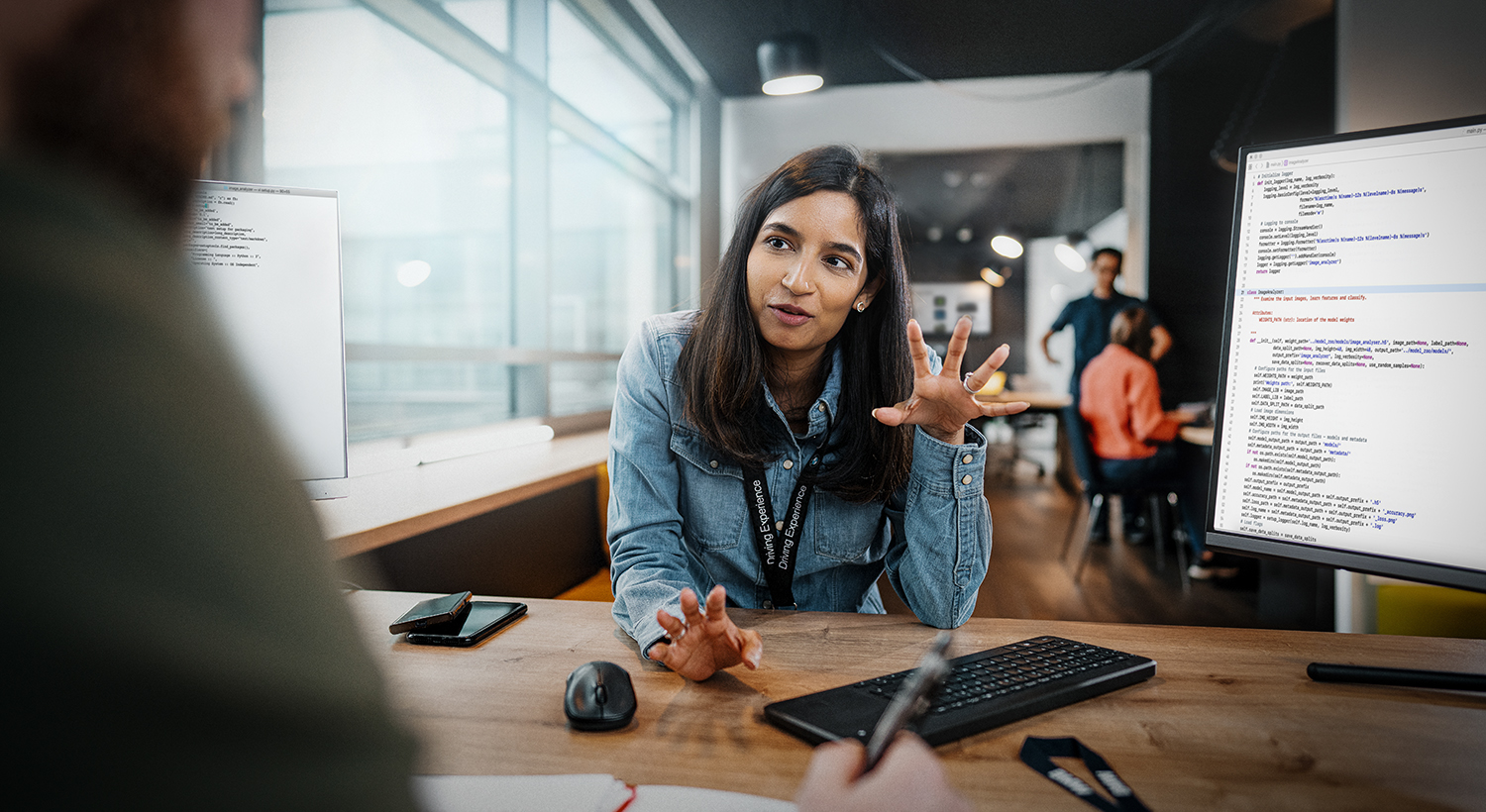 The photo shows a BMW IT employee talking to a colleague.