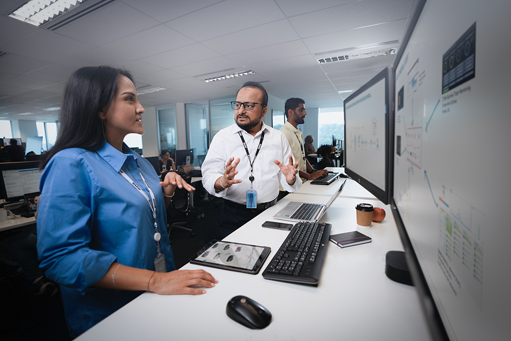 The photo shows a BMW IT employee talking to a colleague.