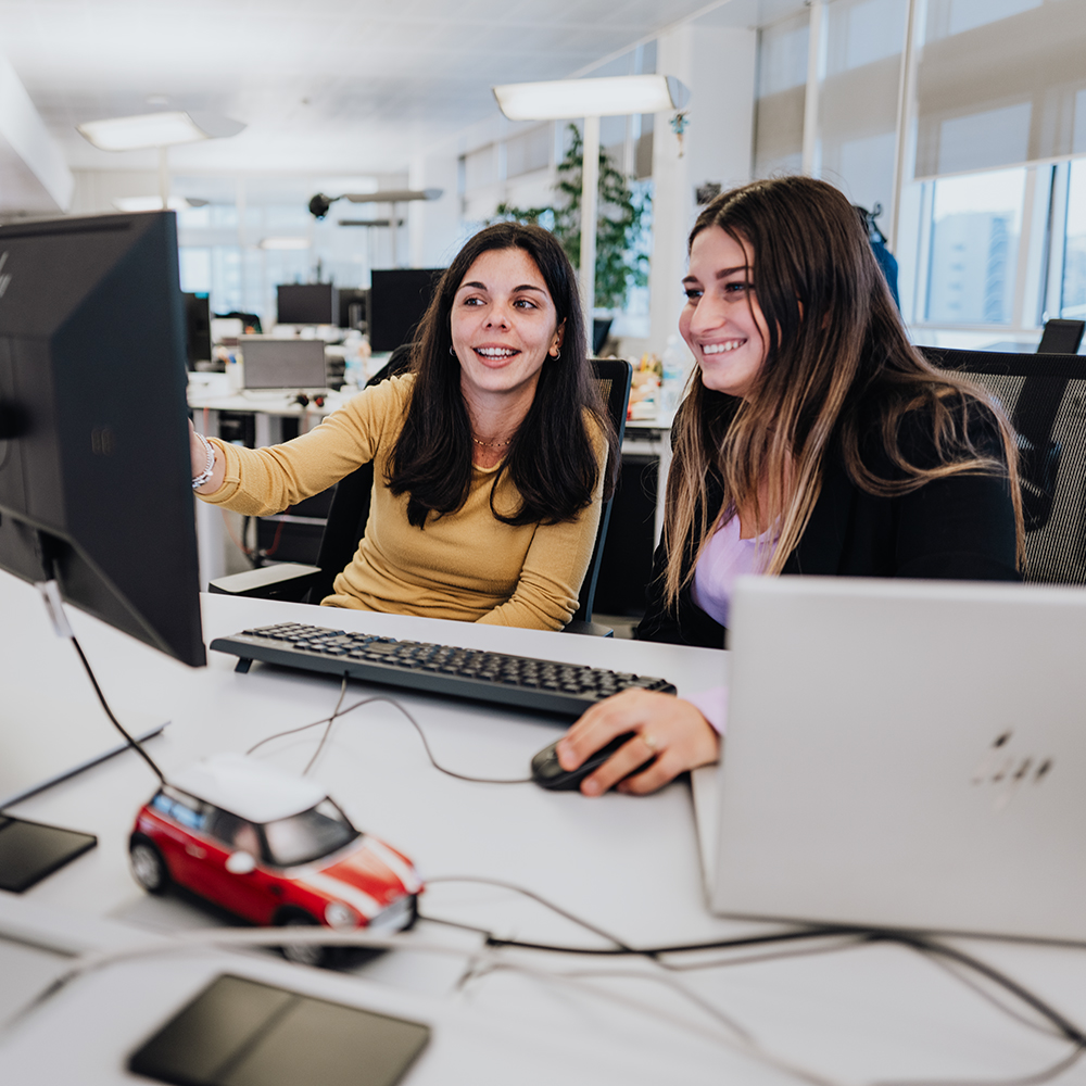 Two colleagues at their desk are having a conversation