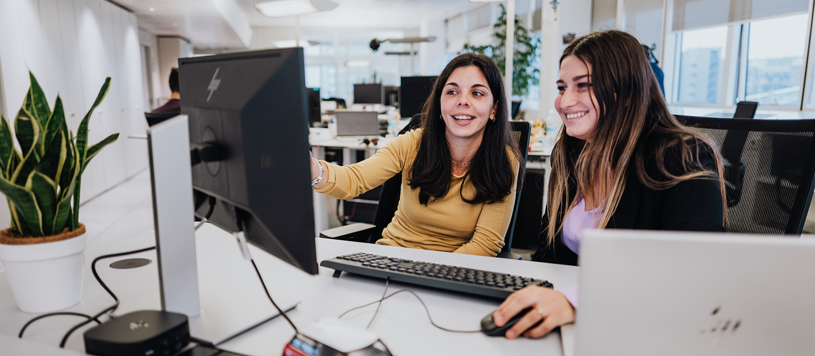 Two people at their desk are talking to each other.