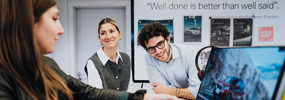 The image shows a group meeting at the BMW Group.