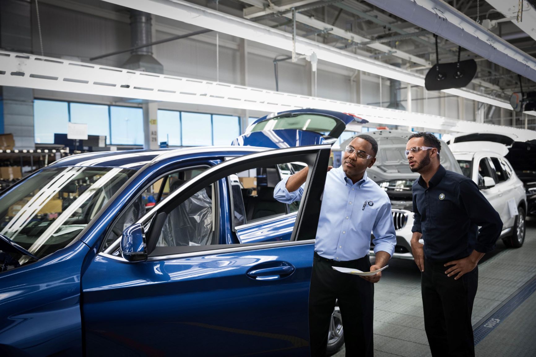 Two BMW quality managers are checking a car.