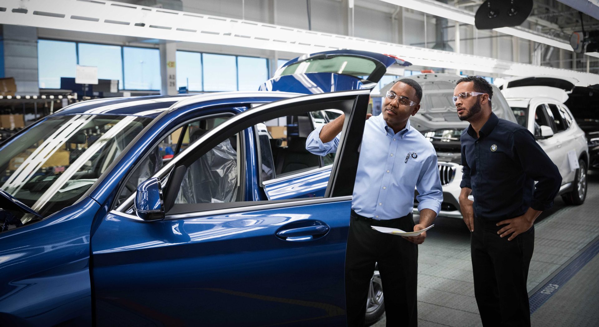 Two BMW quality managers are checking a car. 