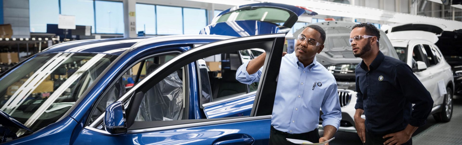 Two BMW quality managers are checking a car. 