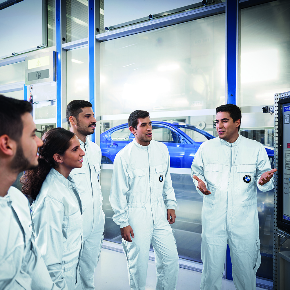 Five BMW paintshop employees discussing something on a screen.