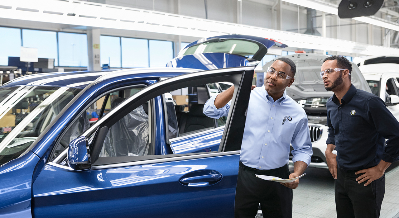 Two BMW quality managers are checking a car. 