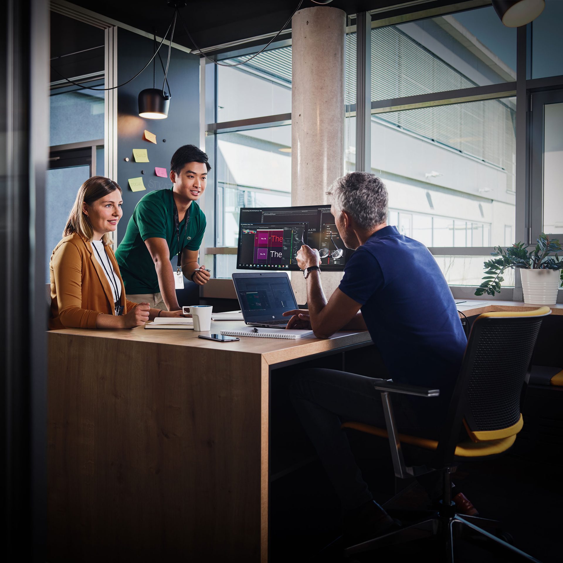 The image shows three colleagues having a conversation.