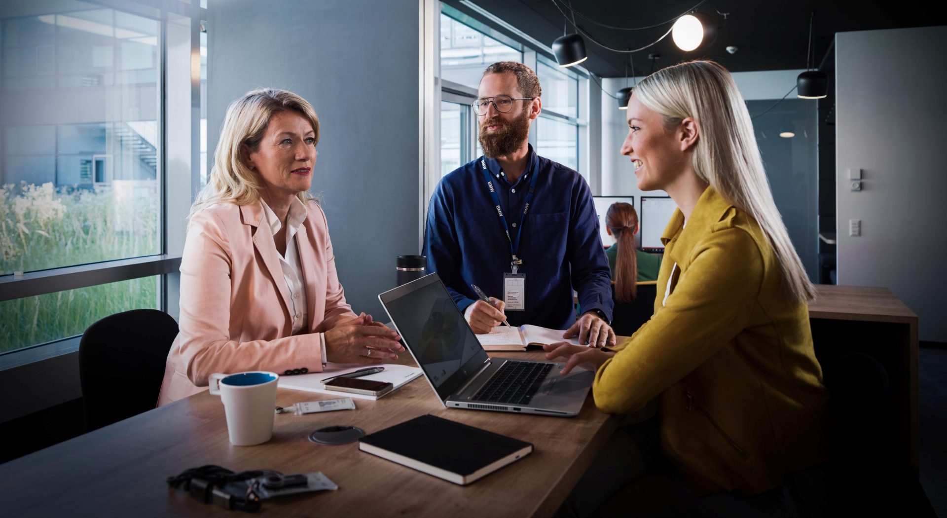 Three BMW professionals, two women and a man, are attending a meeting.