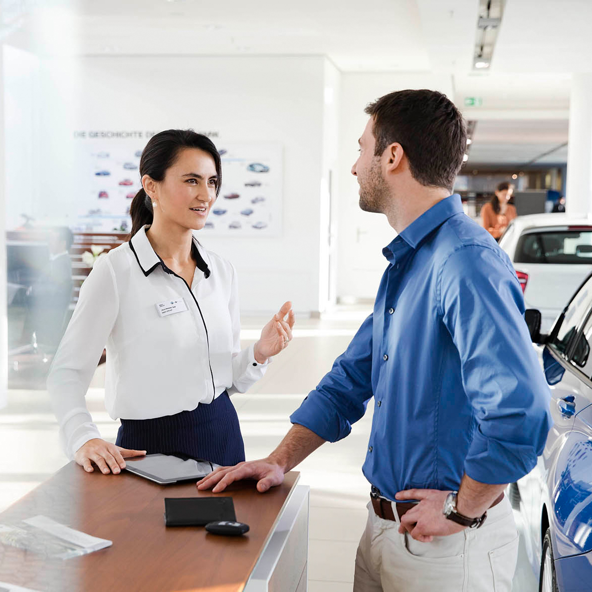 The image shows two BMW Group employees having a conversation.