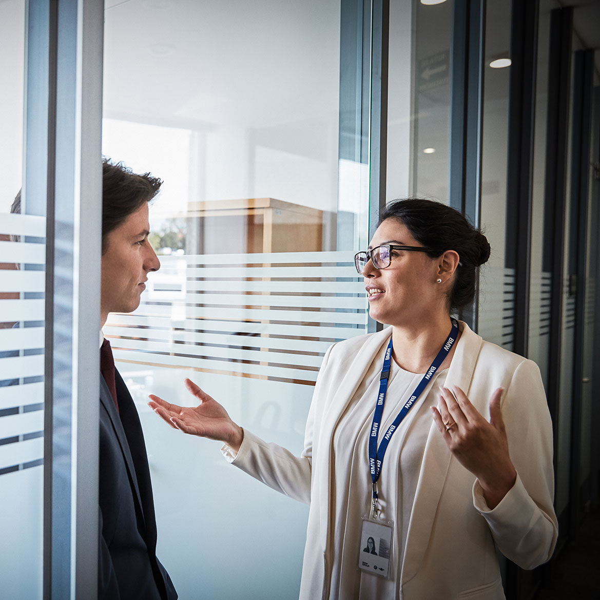 The image shows two BMW Group employees having a conversation.