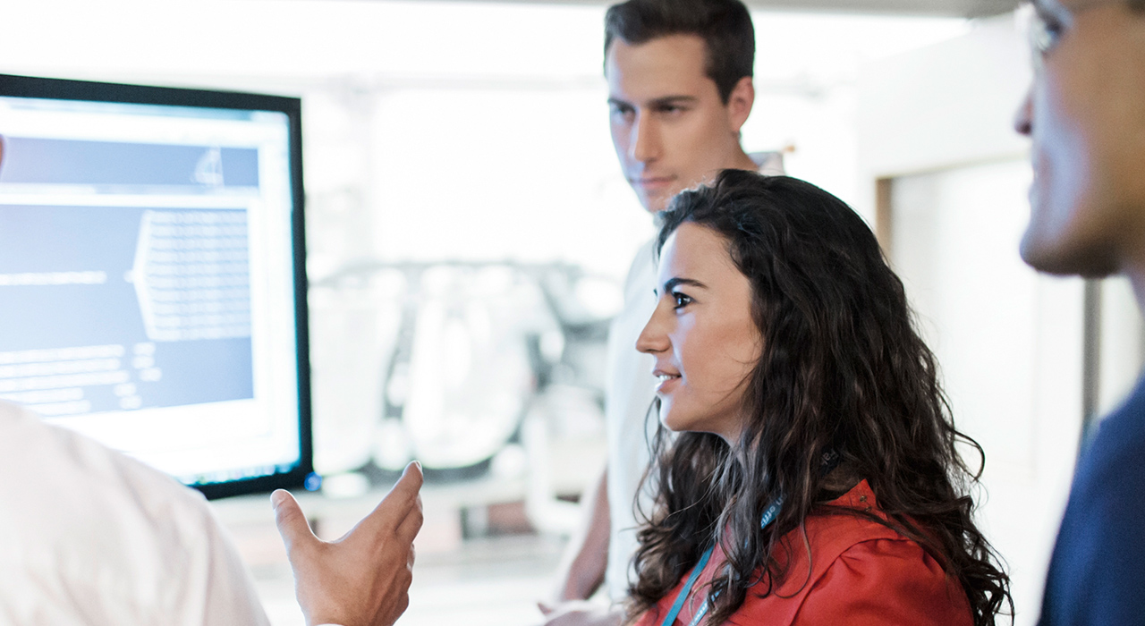 The photo shows four BMW professionals, having a discussion about a diagramm shown on the computer screen.