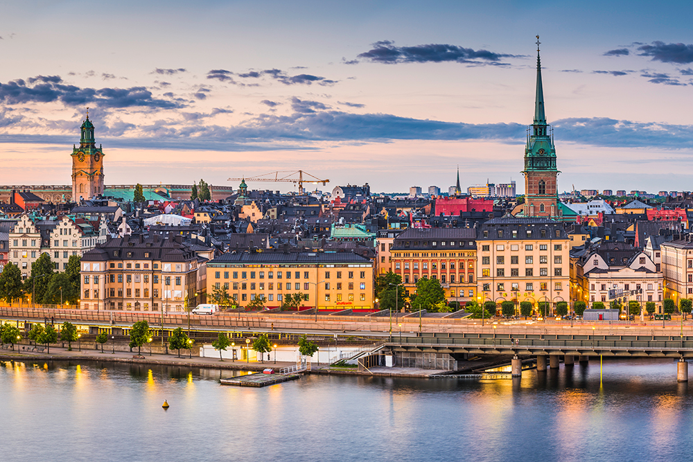 High angle panoramic view across the rooftops and spires of Gamla Stan as the dusk lights illuminate the heart of Stockholm, Sweden's vibrant capital city.