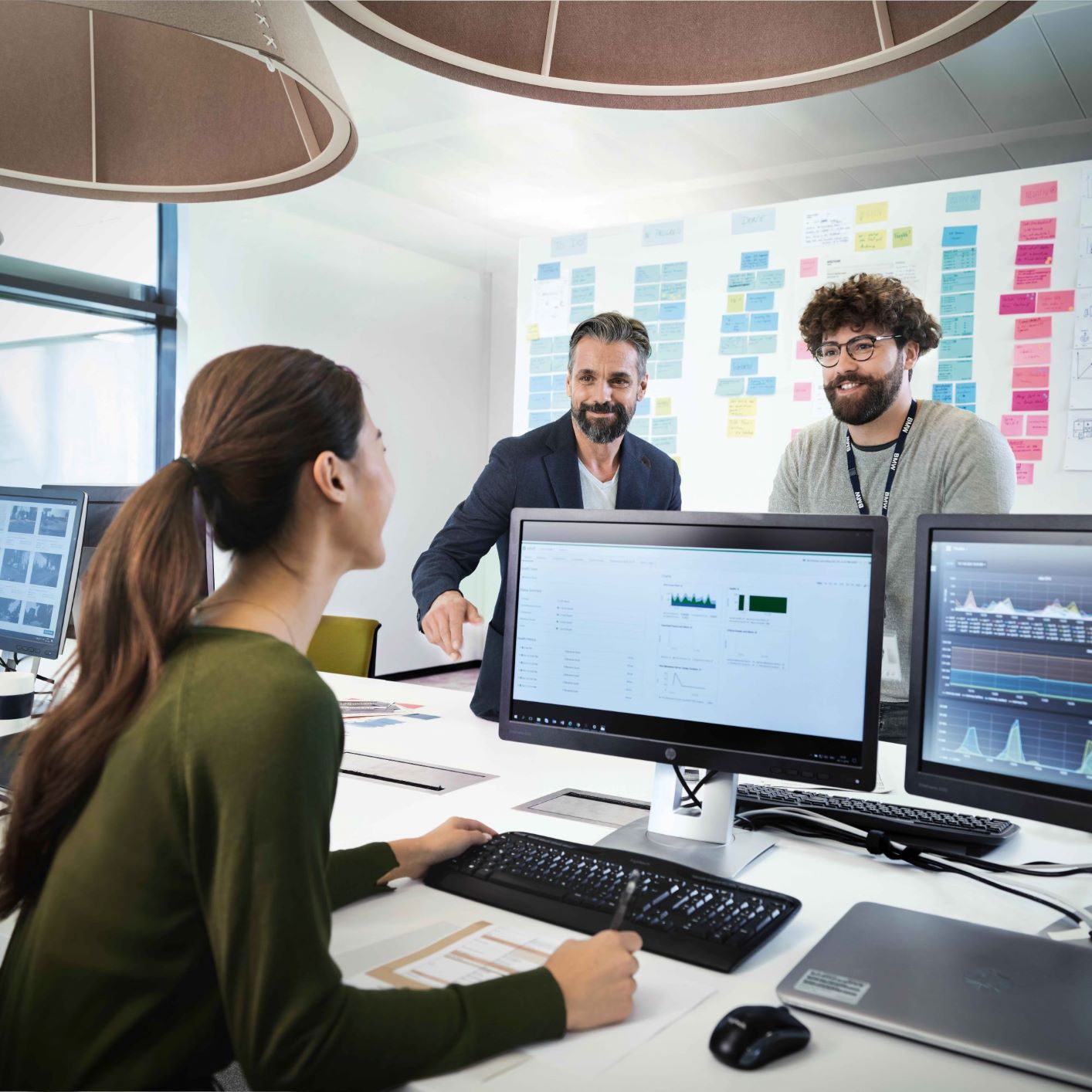 The image shows three BMW Group employees having a meeting.