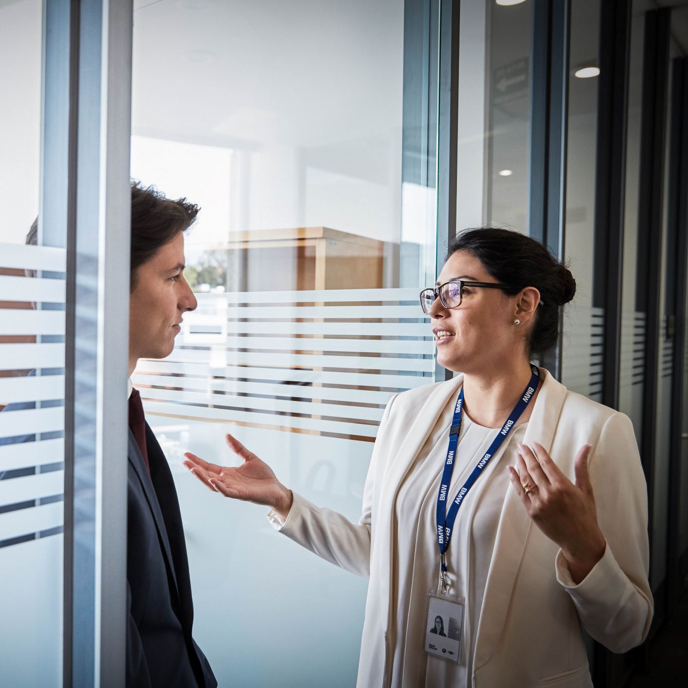 The image shows two BMW Group employees having a conversation.