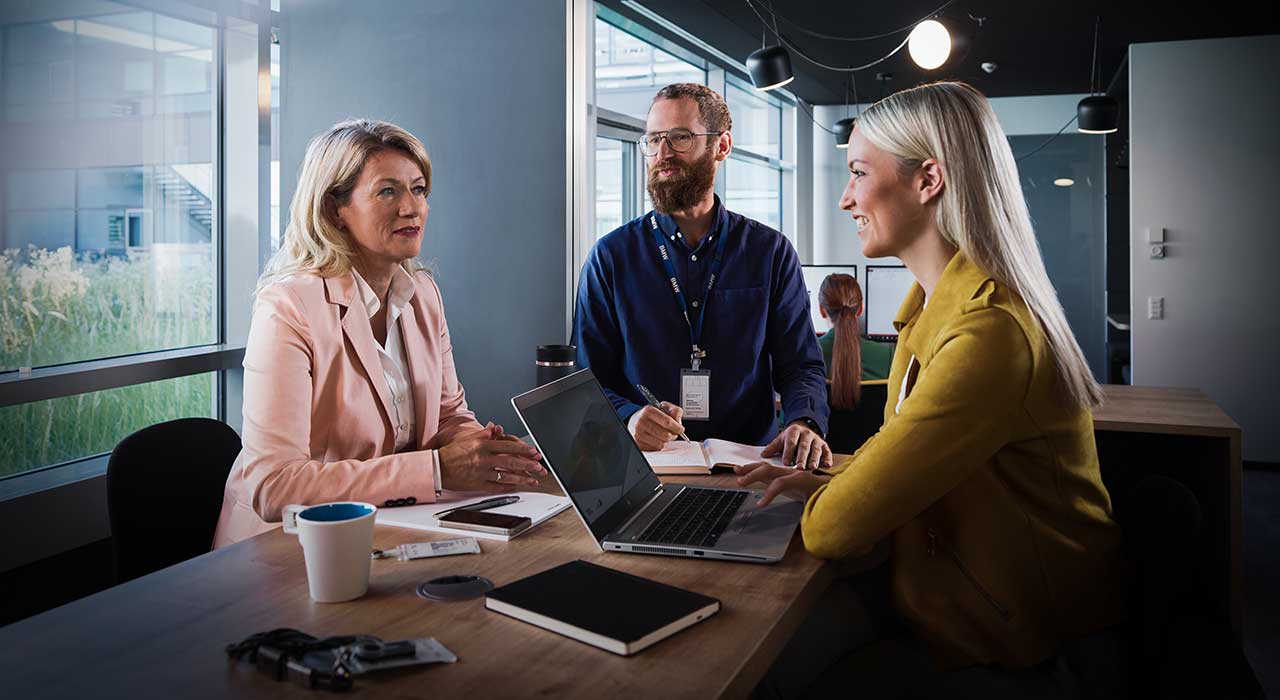 Three BMW professionals, two women and a man, are attending a meeting.