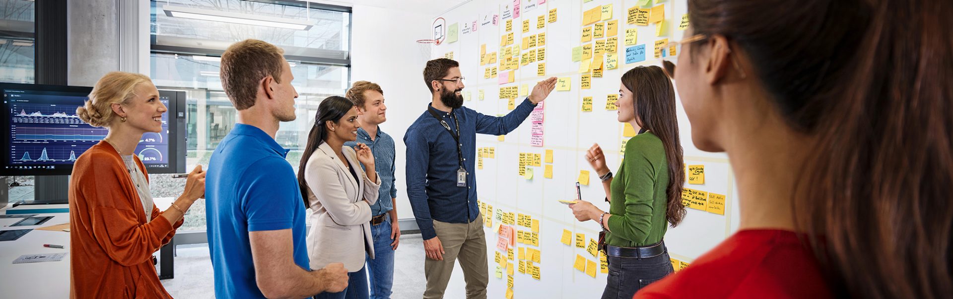 A group of colleagues discuss data on a whiteboard.