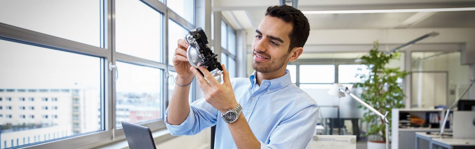 The image shows a BMW Group colleague working in purchasing analysing a prototype.