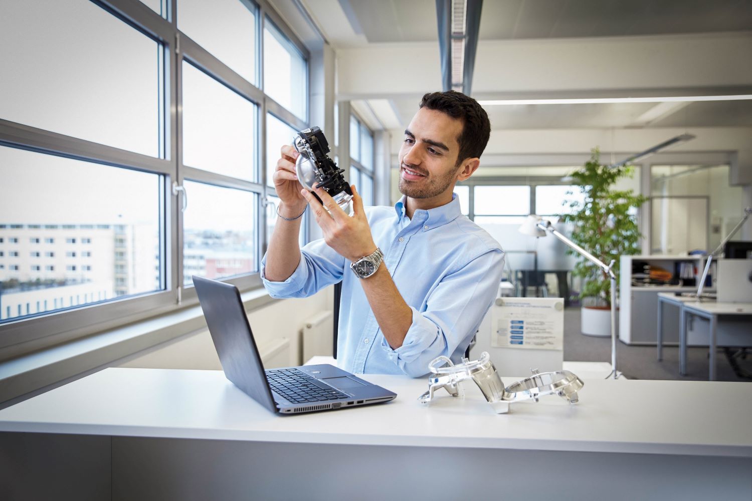 The image shows a BMW Group colleague working in purchasing analysing a prototype.