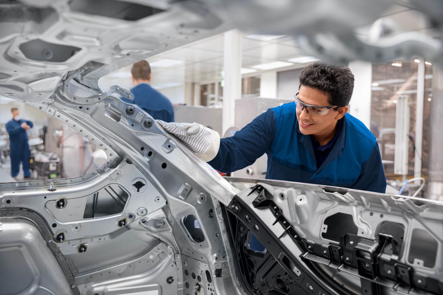 The image shows a BMW Group colleague checking the body in white of a vehicle.
