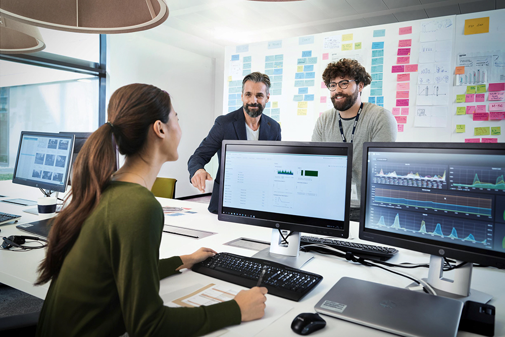 Three BMW professionals, a female one and two male ones, are meeting in an office to discuss a new project.