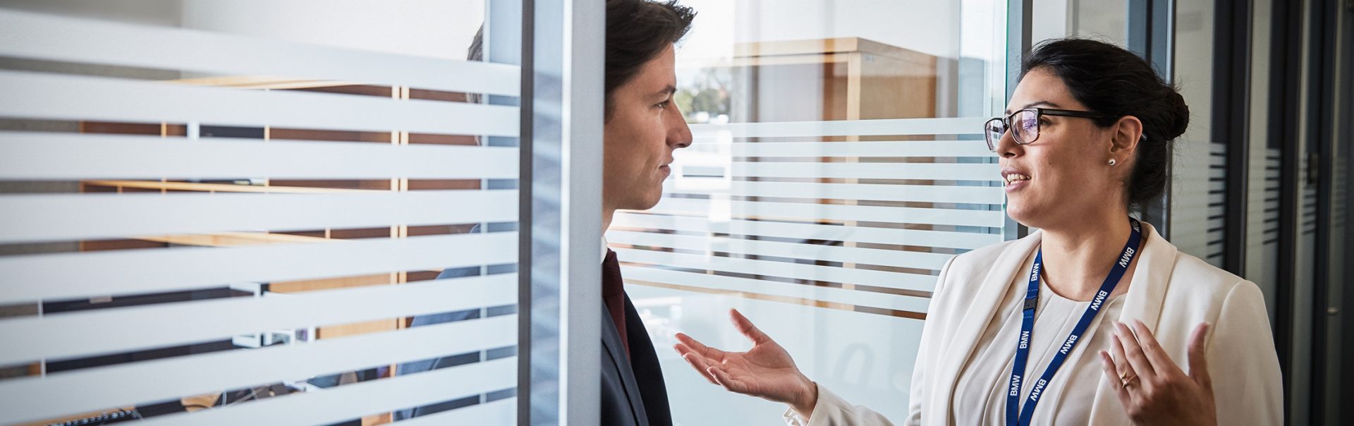 Two colleagues are standing in the doorway talking