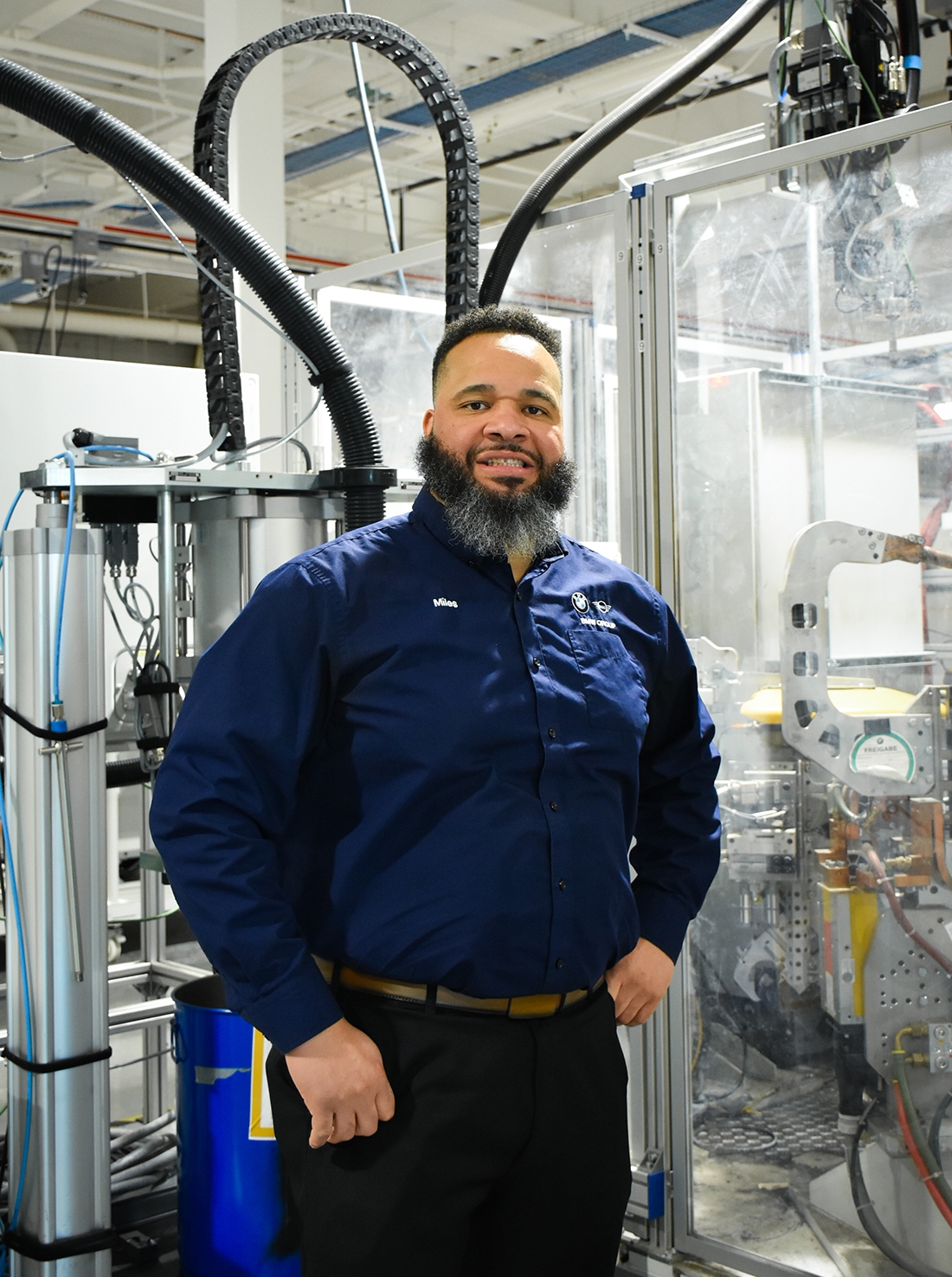 Portrait of BMW Group Maintenance Employee Miles standing in front of a Robot