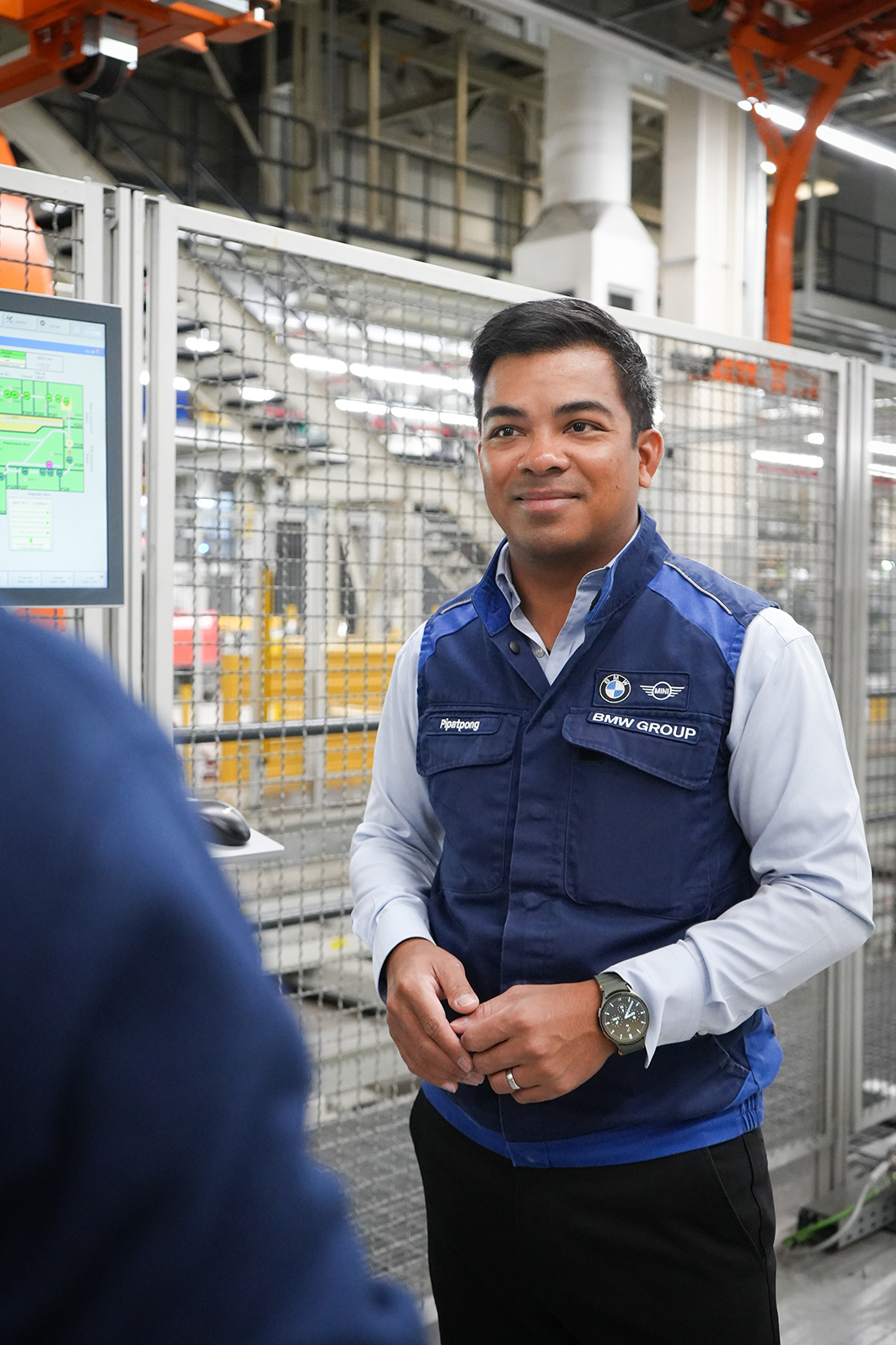 BMW Group employee Pip standing in the production hall and having a chat with a colleague