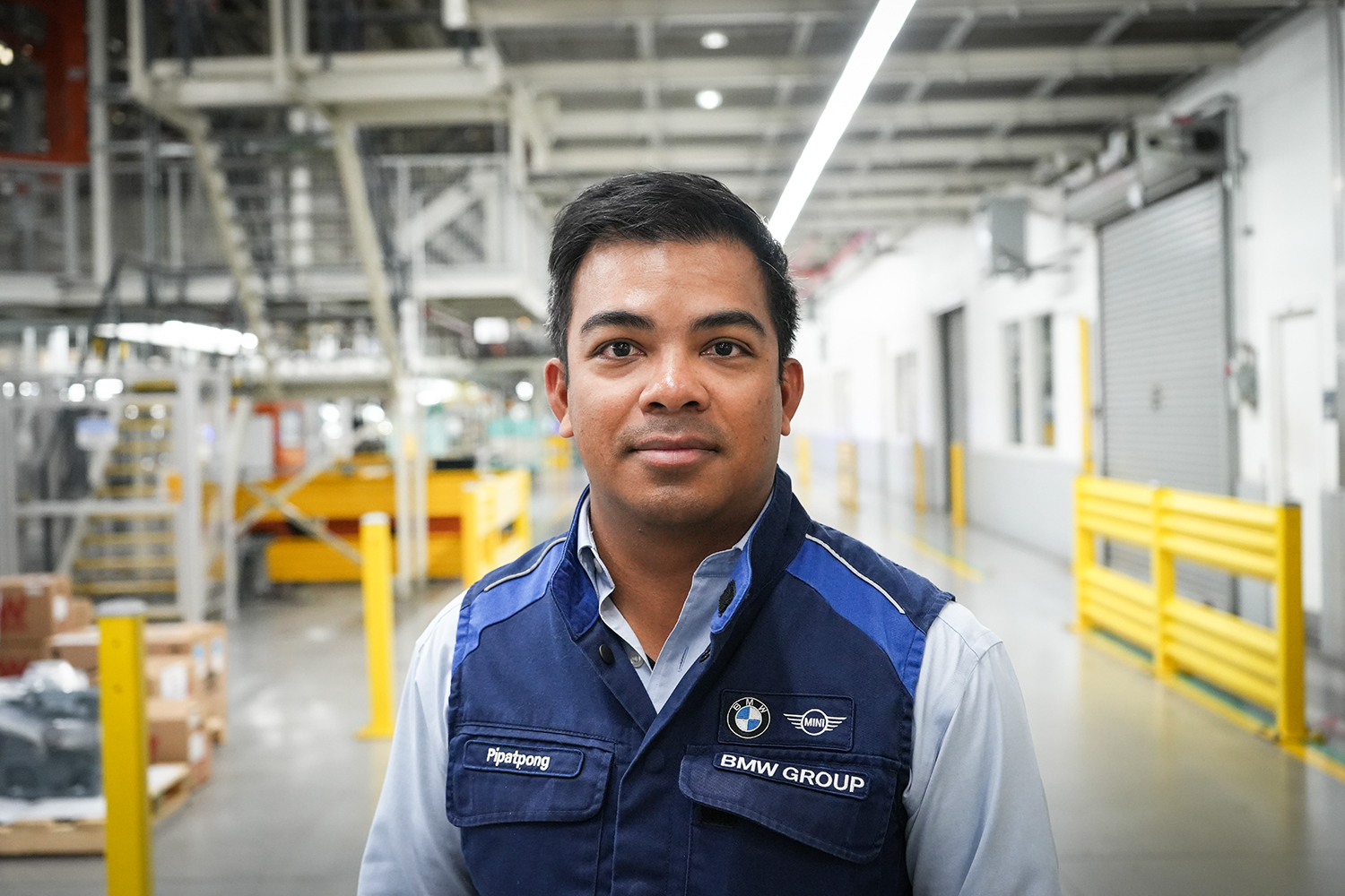 BMW Group employee Pip standing in the production hall and having a chat with a colleague