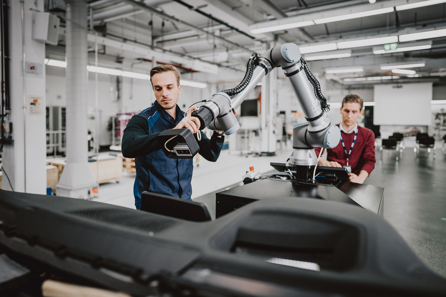 Two logistics employees working with a robot.