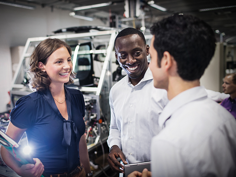 This photo shows three BMW professionals speaking to each other.