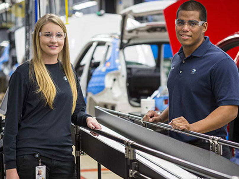Two young employees are working at the assembly line.